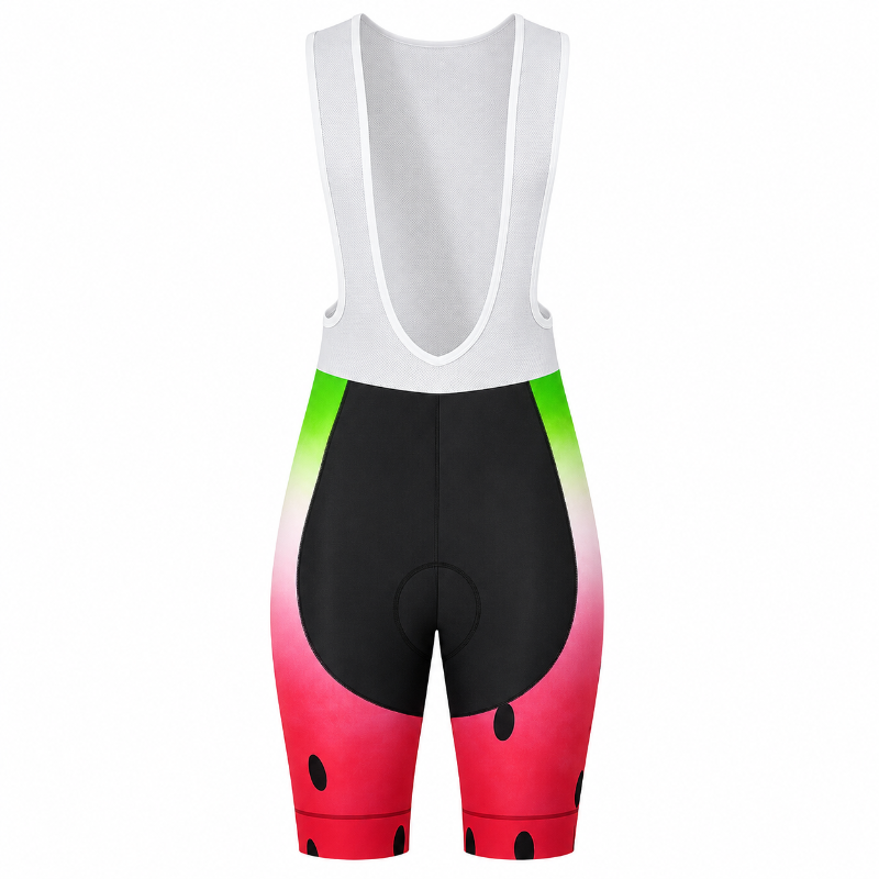 A pair of cycling bib shorts with a watermelon print. The upper portion is white, and the lower portion features a pink-to-red gradient with black seed details, transitioning into a green-to-yellow gradient on the sides.
