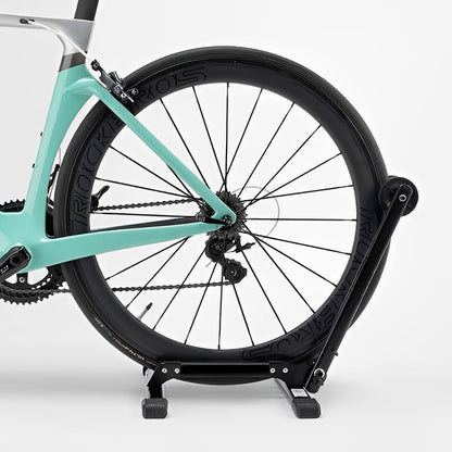 Turquoise bicycle on a black stand against a white background