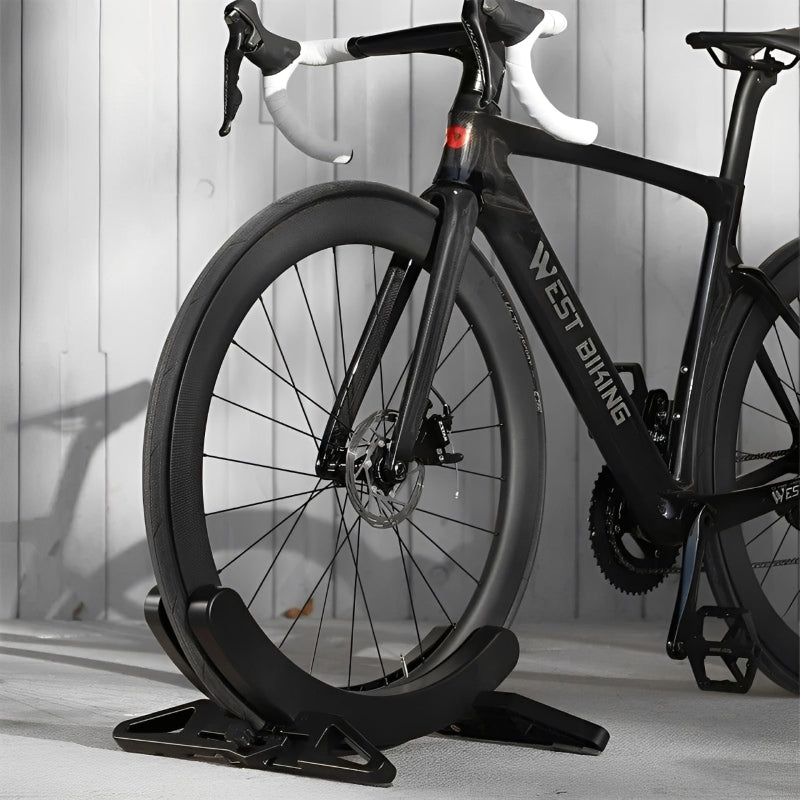 Black bicycle on a stand against a light wooden panel background