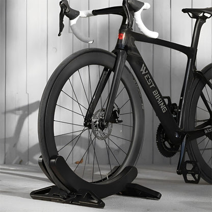 Black bicycle on a stand against a light wooden panel background