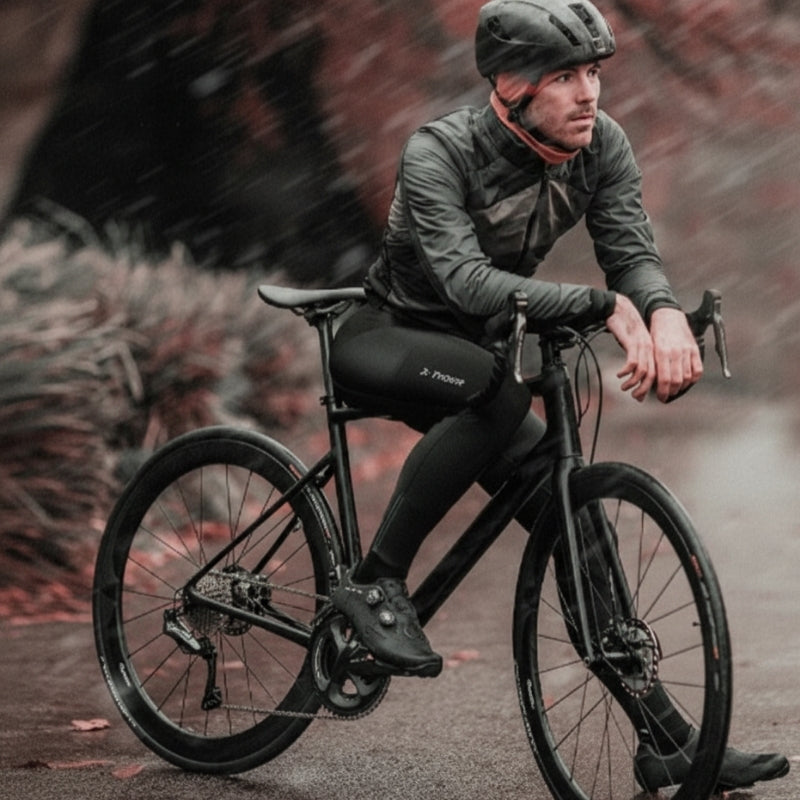 Man riding a black bike on a rainy day
