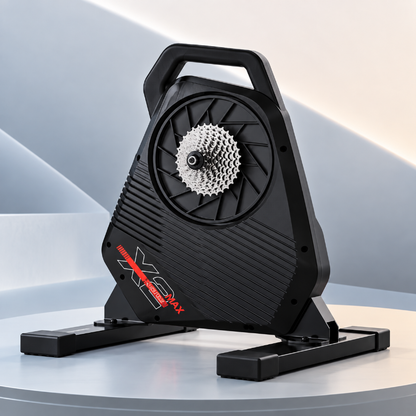 A black indoor cycling trainer with a silver cassette visible through the front wheel cover, shown on a light gray display platform. The trainer has a red and white XPS Pro 4 logo on the lower side.