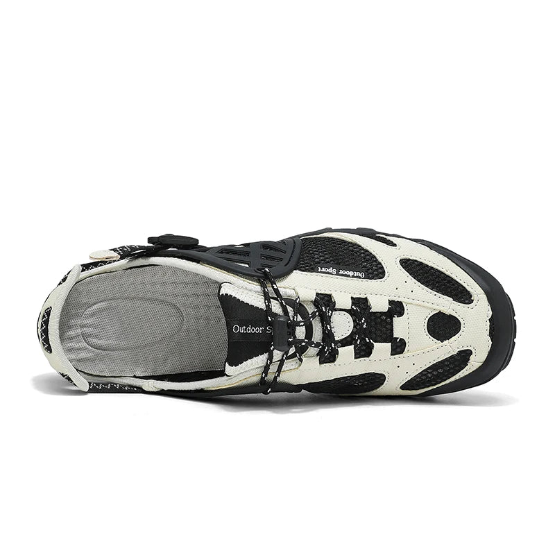 A single outdoor shoe shown from a side profile view on a white background. The shoe features a cream-colored synthetic upper with black mesh panels, black laces, and a black outsole, with a gray textured insole visible.