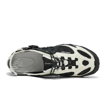 A single outdoor shoe shown from a side profile view on a white background. The shoe features a cream-colored synthetic upper with black mesh panels, black laces, and a black outsole, with a gray textured insole visible.