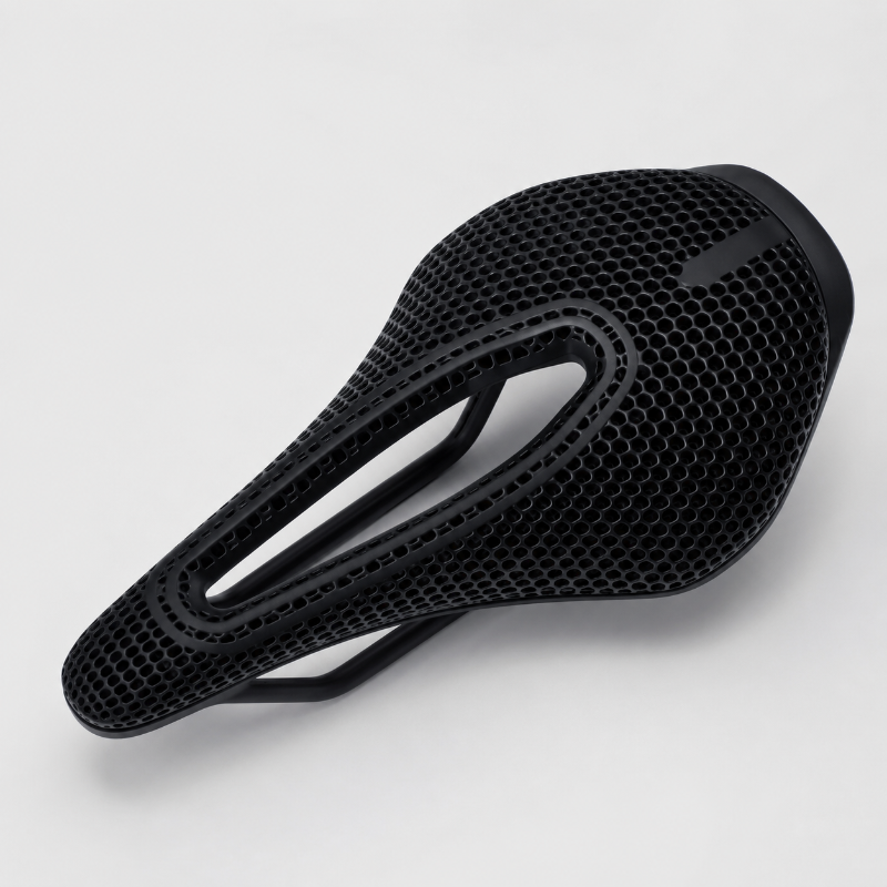 A black bicycle saddle with a textured honeycomb mesh pattern, shown from a three-quarters perspective on a light gray background.