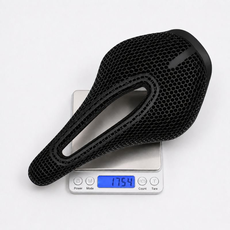 A black bicycle saddle with a honeycomb-textured surface, shown resting on a digital scale that displays a weight of 175.4 grams.