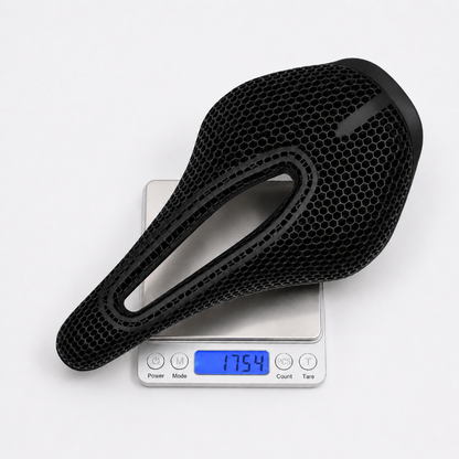 A black bicycle saddle with a honeycomb-textured surface, shown resting on a digital scale that displays a weight of 175.4 grams.