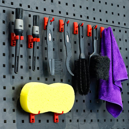 Set of cleaning tools including brushes, a sponge, and a towel on a pegboard.