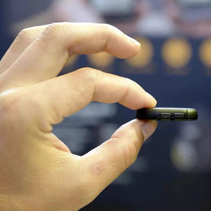 Hand holding a small black device with a blurred background