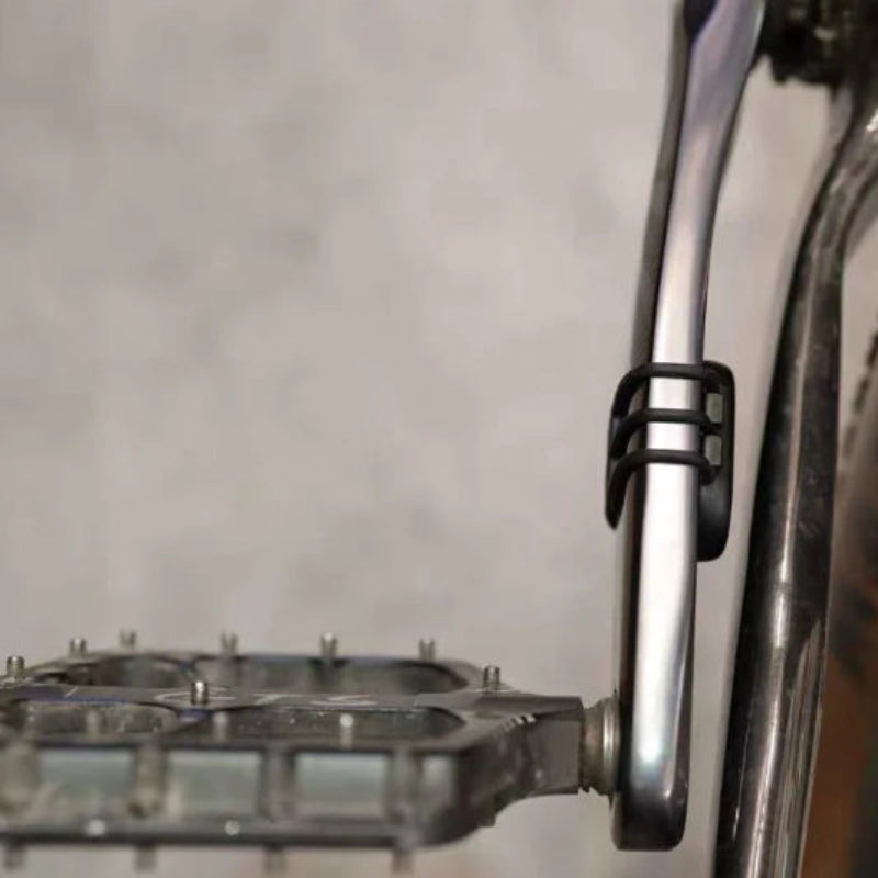 Close-up of a bicycle exhaust and foot pegs on a textured gray background