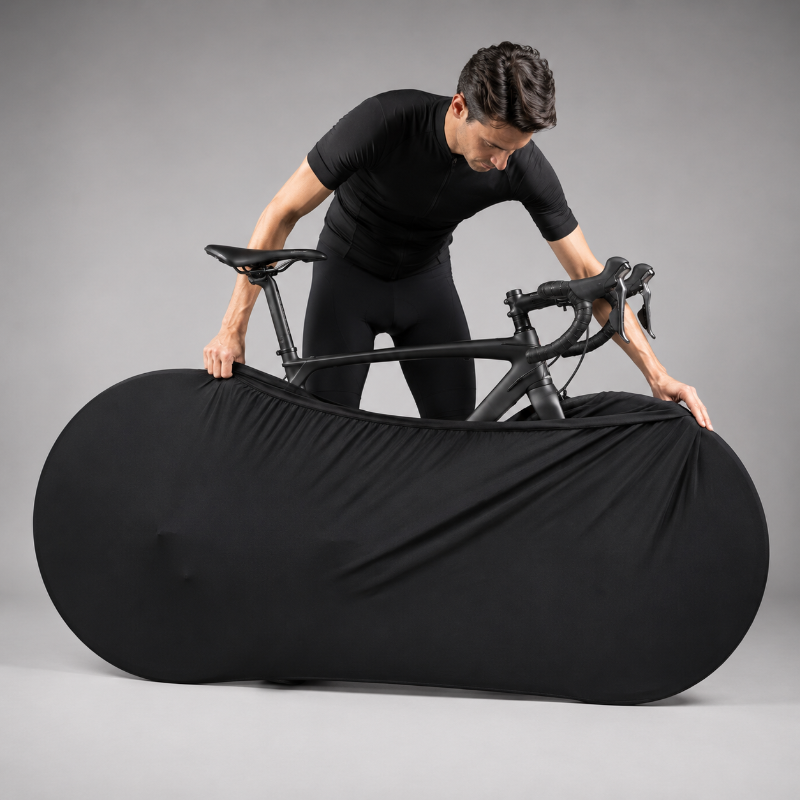 Person holding a black bicycle wrapped in a cover against a gray background