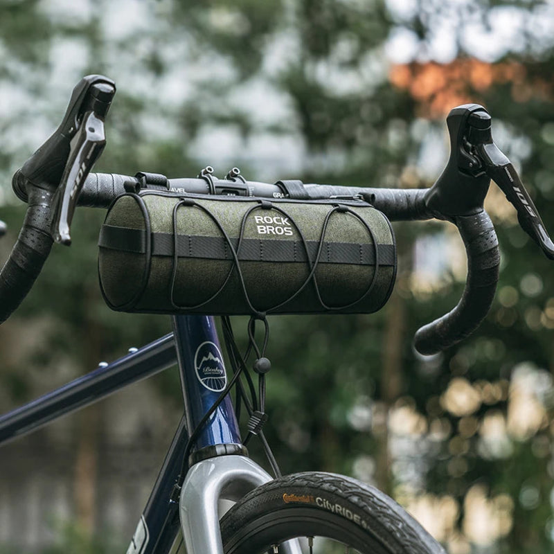 Bicycle handlebar with a green bag against a blurred natural background