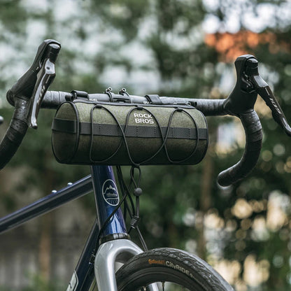 Bicycle handlebar with a green bag against a blurred natural background