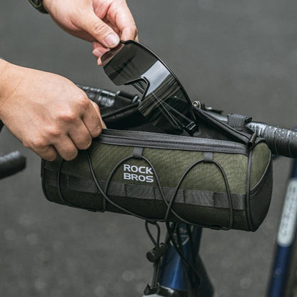 Person attaching a green bicycle handlebar bag to a bike.