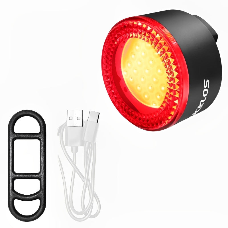 Red bicycle tail light with USB cable and black clip on a white background