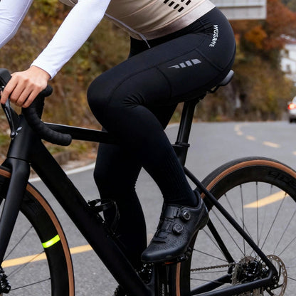 Person riding a bicycle on a road with black cycling pants featuring a brand logo.