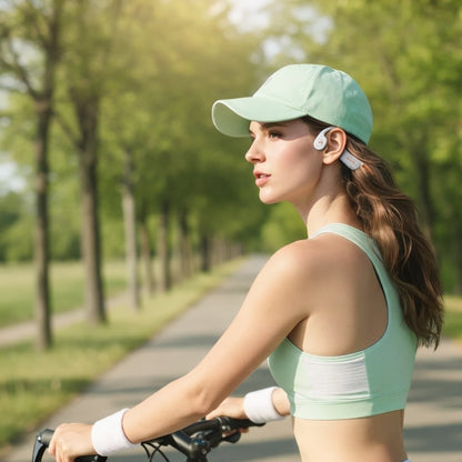 Woman in athletic wear and cap riding a bike on a tree-lined path