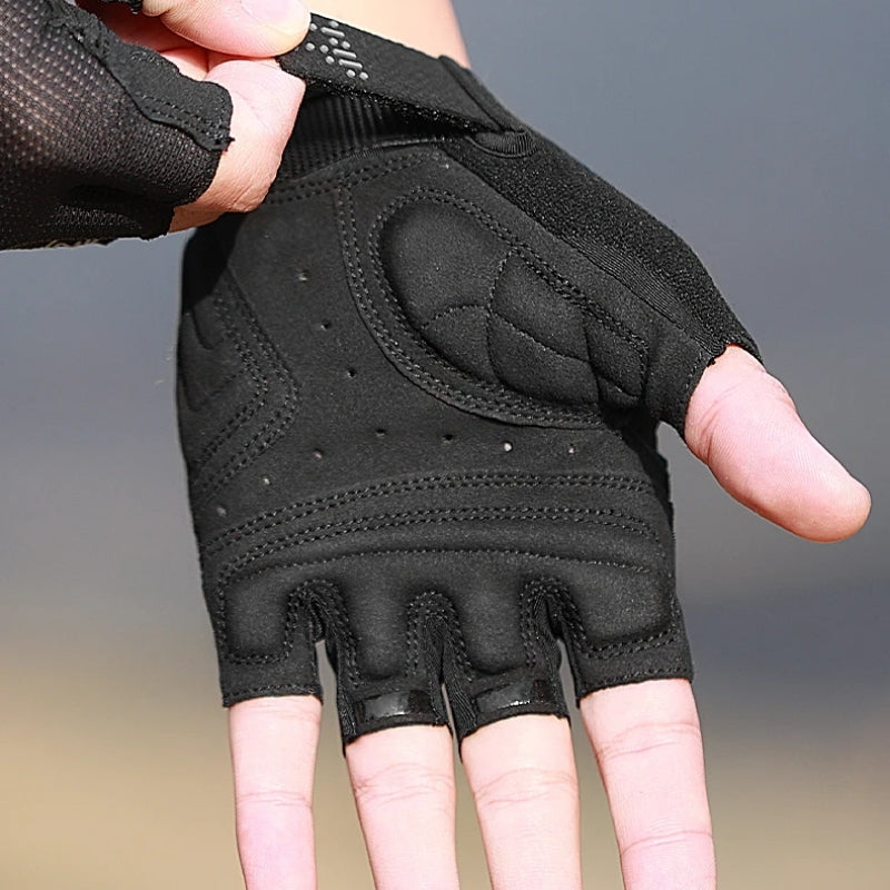 Black half-finger glove held by a hand against a neutral background
