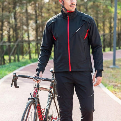 Man in black cycling jacket with red zippers holding a bicycle on a path in a park.