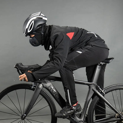 Person wearing a black helmet and black outfit with a red logo, riding a black bicycle on a gray background