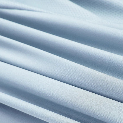 Light blue textured fabric with soft diagonal folds and pleats, shown in a close-up view.