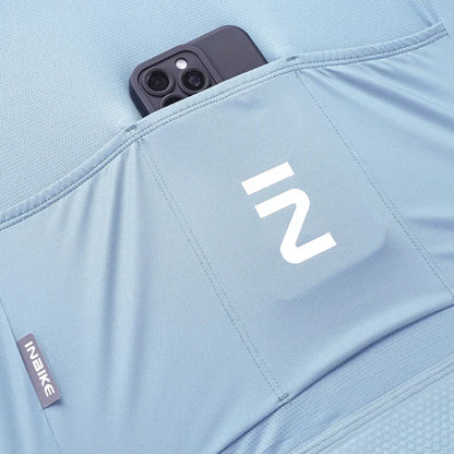 Close-up of a light blue athletic garment with a front pocket holding a dark smartphone. 