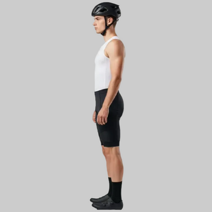 Person wearing a white sleeveless shirt, black cycling shorts, and a helmet on a gray background