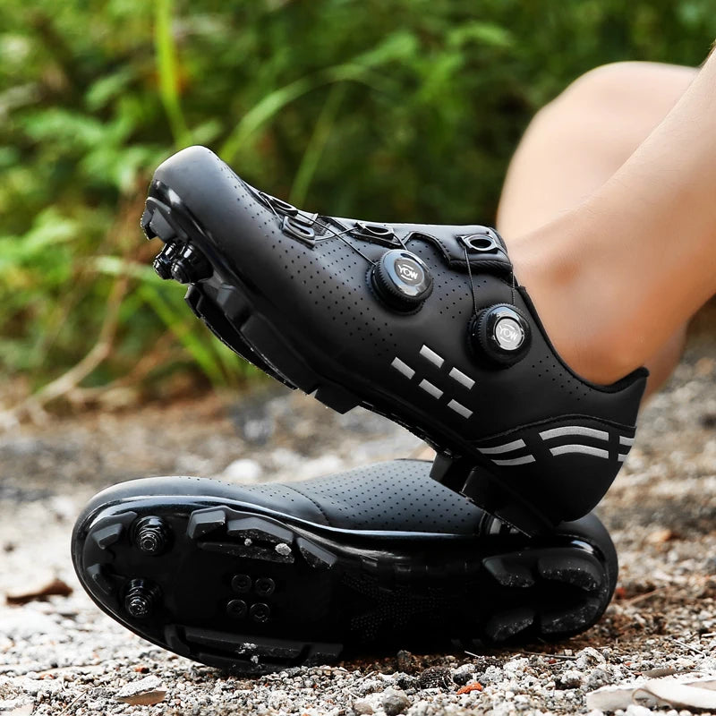 Black cycling shoes on a gravel surface with greenery in the background