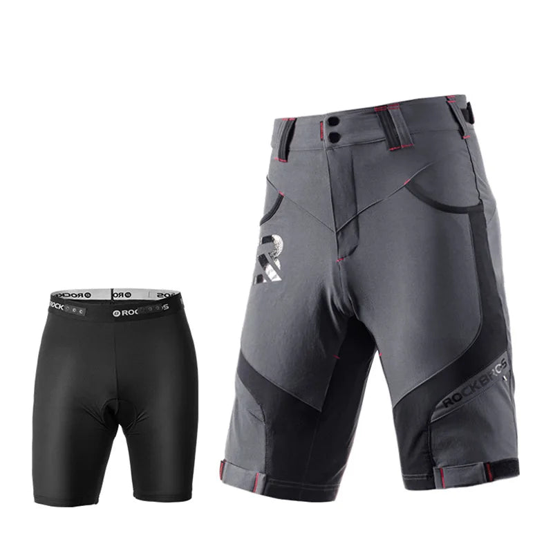 A pair of dark gray and black technical riding shorts with red stitching details, shown alongside a matching black compression brief on a solid white background.