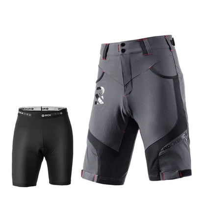 A pair of dark gray and black technical riding shorts with red stitching details, shown alongside a matching black compression brief on a solid white background.