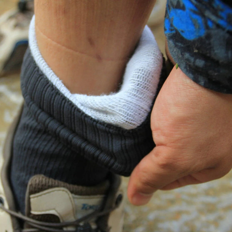 Close-up of a person adjusting a sock on a shoe with a blurred background