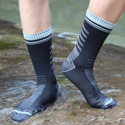 Person wearing black socks with white stripes standing in water.