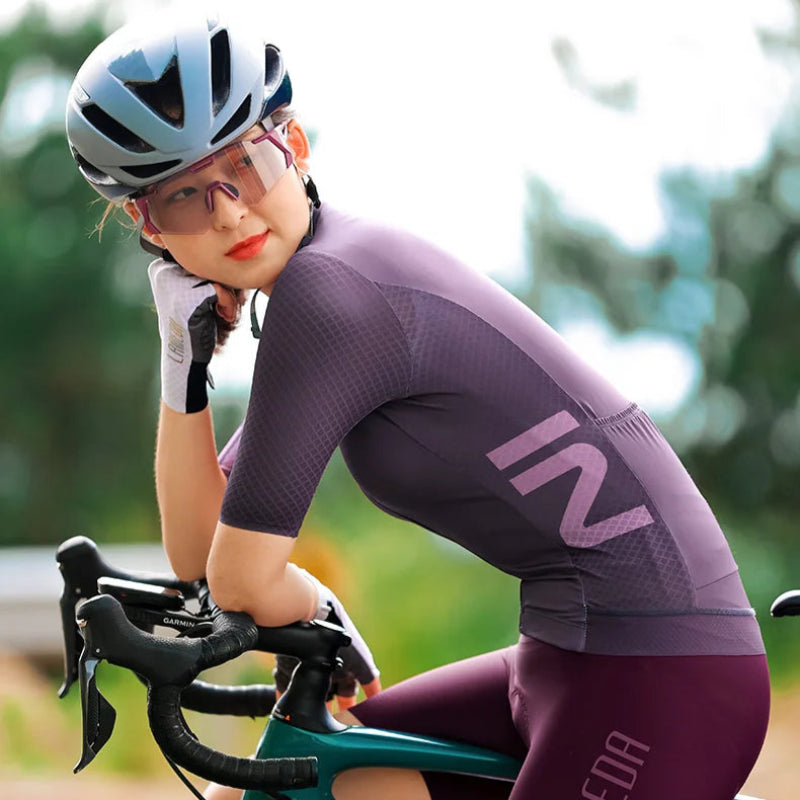 Person wearing a cycling outfit with visible branding on a blurred natural background