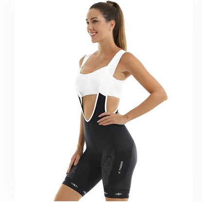 Woman wearing a white sports bra and black cycling bib shorts on a white background